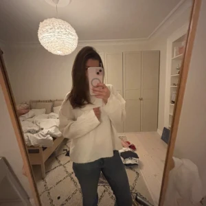 Vit stickad tröja med rund hals - Mysig vit stickad tröja med rundad halsringning och långa ärmar. Tröjan har en relaxed passform och ribbade muddar vid ärmslut och nederkant. Perfekt för lager-på-lager under kyliga dagar.