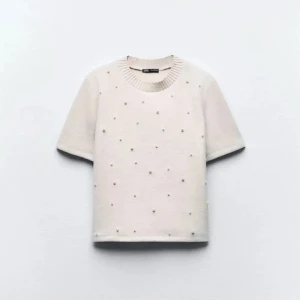 Vit pärlprydd topp från Zara - Superfin vit topp från Zara med korta ärmar och croppad passform. Toppen är dekorerad med små pärlor över hela framsidan och har en ribbad rund halsringning. Perfekt för dig som gillar stilrena detaljer och vill sticka ut lite extra.
