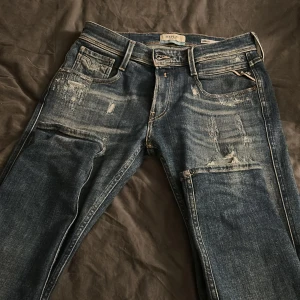 Replay Anbass blå slitna jeans - Säljer ett par Replay Anbass jeans i blå tvätt med slitningar och distressed detaljer. Jeansen är nästan aldrig använda, därför säljs de så dyrt. Köpta på NK i Göteborg, kvitto finns