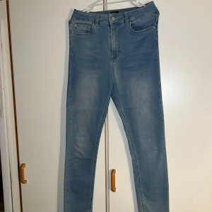 Ljusblå skinny jeans från NLY Jeans - Snygga ljusblå skinny jeans från NLY Jeans med klassisk femficksdesign och dragkedja i gylfen. Jeansen har slits nertill på benen för en trendig touch. Perfekta för dig som gillar en tight passform och stilren look.