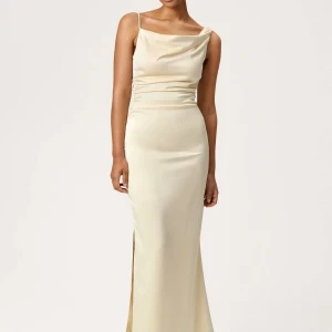 Champagnefärgad långklänning i satin - Elegant långklänning i champagnefärgad satin med smala axelband. Klänningen har en figurnära passform och en slits på sidan. Perfekt för bal. Snygg asymmetrisk rygg, man kan både ha klänningen som på hemsidan eller off shoulder. Använd 1 gång, så i mycket bra skick. 🥰 Använde min själv på balen och kände mig så fin! Ordinariepris 1 595kr. 🥰pris kan diskuteras. 