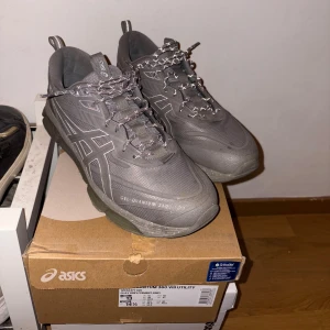 Grå Asics Gel-Quantum 360 VIII sneakers - Säljer ett par grå Asics Gel-Quantum 360 VIII sneakers med reflekterande snören och tydlig Asics-logga på sidorna. Skorna har en chunky sula och är tillverkade i syntetmaterial med mesh för extra andningsförmåga. Perfekta för dig som gillar sportig stil.