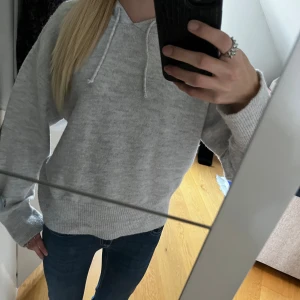 Ljusgrå stickad hoodie med luva - Mysig ljusgrå stickad hoodie med luva och snörning. Tröjan har ribbade muddar vid ärmslut och nederkant, samt en relaxed passform.  Perfekt för kyliga dagar! Barnstorlek 170 men passar som xs/s och i nyskick🩶🍂