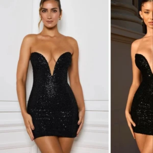 Svart glittrig kort klänning - Supersnygg svart paljettklänning med djup v-ringning och öppen rygg. Klänningen är axelbandslös och har en tight passform som framhäver figuren. Kort längd och glittrigt material gör den till ett riktigt statement-plagg. Perfekt för dig som vill sticka ut.