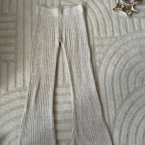 Beige ribbade bootcut lågmidjade byxor - Säljer ett par beige ribbade byxor med bootcut-modell. De har hög midja och är tillverkade i ett mjukt, stickat material som känns riktigt skönt. Perfekta för en chill och trendig look.