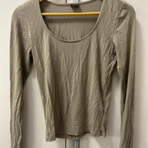 Beige långärmad topp Gina Tricot - Enkel och stilren grön långärmad topp från Gina Tricot. Modellen har rund halsringning och är figurnära i passformen. En populär tröja men kommer tyvärr inte till användning. Storlek M