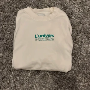 Vit sweatshirt från Vaillent S - Vit sweatshirt från Vaillent i storlek S med trycket 'L'univers Parallèle' i grönt framtill. Tröjan har rund halsringning och är tillverkad i mjuk bomullsblandning. Nypris 900, sällan använd
