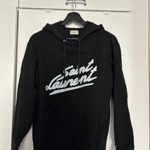 Saint Laurent Hoodie - Säljer nu min Saint Laurent hoodie. Köpt här på plick och kan inte garantera att den är äkta etftersom den saknar vissa tags. Därav är priset lägre. Tröjan är fortfarande i väldigt bra skick och går lätt att bära. Storlek S och sitter som en S/Xs
