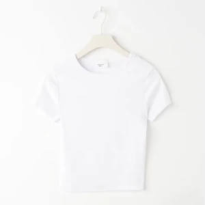 Vit croppad t-shirt i bomull - Enkel och stilren vit croppad t-shirt med rund halsringning och korta ärmar. Tillverkad i mjuk bomull som känns skön mot huden. Perfekt att matcha med jeans eller kjol för en clean look.