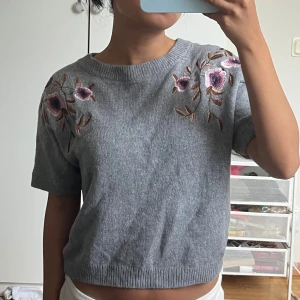 Grå stickad topp med blommor Massimo Dutti - Superfin grå stickad topp från Massimo Dutti med broderade blommor i lila och rosa på axlarna. Knappt använd!