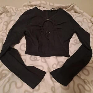 Svart croppad topp med cut-out  - Svart croppad topp från Zara med lång ärm och cool cut-out detalj framtill med metallring och snörning.  Dragkedja i ryggen  och vid sidan. 😊🩷
