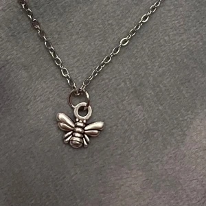 Choker Bi Halsband Silver Imitation  - Så fin choker med en liten berlock av ett bi 🐝 Trädd på kedja i silverimitation, justerbar 35-40 cm. Berlocken är ca 1 x 0,8 cm.  