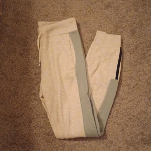 Adidas  mjukisbyxor - Ljusgrå lågmidjade tajta mjukisbyxor från Adidas i storlek XS. Byxorna har gröna sidopaneler, svarta ränder vid benslutet och Adidas-logga längs benet. Resår i midjan med snörning och mjukt bomullsmaterial för skön passform. Nästan aldrig använda men väldigt sköna!🍃🩶 Det är bara att skriva om man har frågor!😊💖