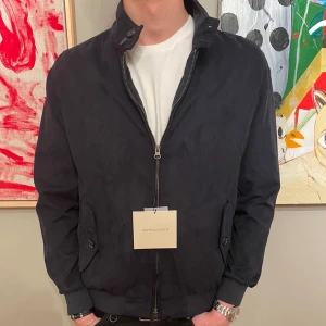 Mörkblå mockajacka från Doppelgänger - Snygg mörkblå jacka från Doppelgänger med dragkedja och ribbade muddar. Jackan har en stilren design med två knappar på fickorna och en hög krage. Perfekt för en cool och avslappnad look. Obs tags medföljer ej!