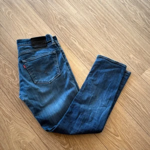 Levi's 511 jeans - Snygga blå Levi's 511 jeans med klassisk femficksdesign och smal passform. Jeansen har mellanblå tvätt, tydliga sömmar och svart patch bak i midjan. Perfekta för dig som gillar en modern och stilren look. passar dig som är runt 168/173!