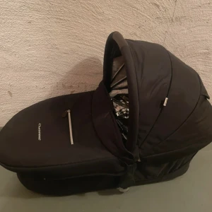 Crescent barnvagn - Snygg Crescent barnvagn i svart med liggdel och sittdel. Vagnen ser välvårdad ut med endast mindre bruksspår. Perfekt för både nyfödda och småbarn, med robust ram och bekväm sits. Passar för både stad och terräng.