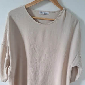 Beige blus från Paul Mark i XL - Snygg beige blus från Paul Mark i storlek XL. Blusen har rund halsringning och trekvartsärmar med knappdetalj. Tillverkad i ett mjukt och lätt material som ger en chill och avslappnad vibe. Perfekt för dig som gillar enkel och stilren design. Obehandlad fläck finns. 