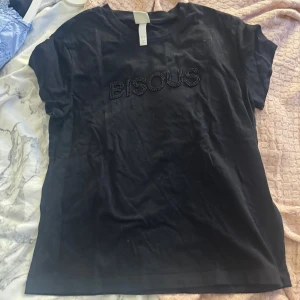 Svart t-shirt med pärltext BISOUS - Jättefin T-shirt från hm, säljs inte längre. Inte alls mycket använd .
