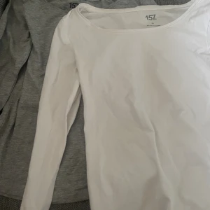 2 långärmade tröjor - Två basic långärmade tröjor från 157 i storlek XS. En är vit och tillverkad i bomull och elastan, den andra är grå och gjord av bomull, viskos och elastan. Båda har rund halsringning och en enkel, klassisk passform.