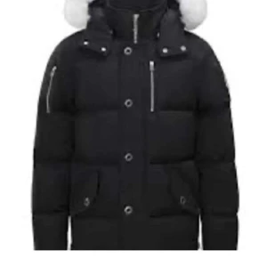 Moose knuckles jacka - Moose Knuckles vinterjacka En varm och stilren jacka som klarar kalla vintrar. Den är gjord av slitstarkt material, har mjuk dunfyllning och en huva med päls. Perfekt för både vardag och stadsliv – håller dig varm och snygg hela vintern.