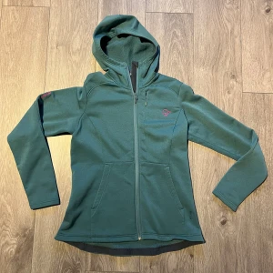 Grön fleecetröja Norrøna - Säljer en grön fleecejacka från Norrøna Narvik med huva och hel dragkedja. Jackan har två fickor fram, broderad logga i rosa på bröstet och mjukt fleecefoder på insidan. Perfekt för kyliga dagar och outdoor-häng.