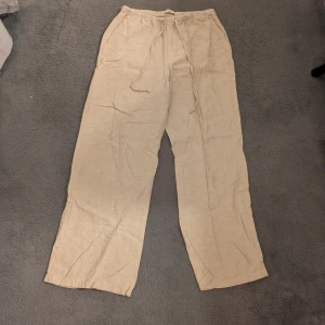 Beiga linnebyxor med snörning - Snygga och avslappnade beiga linnebyxor med breda ben och elastisk midja med snörning. 