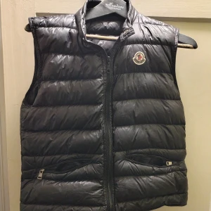 Moncler väst - De är en svart Moncler väst som är i toppen skick och  de enda som jag har gjort är att byta ut drag kedjan därför den inte har Moncler egna dragkedja.
