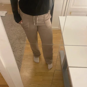 Beige mjukisbyxor med snörning - Beiga mjukisbyxor från 157 i storlek S. Byxorna har resår och snörning i midjan, raka ben och stora fickor fram och bak. Mjukt och skönt material, perfekta för chill dagar hemma eller när du vill vara bekväm.
