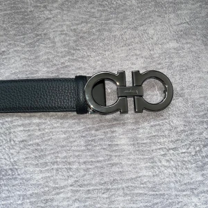 Svart skärp från Salvatore Ferragamo - Säljer ett svart bälte från Salvatore Ferragamo i exklusivt skinn med en ikonisk dubbel Gancini-spänne i metall. Bältet har en stilren och lyxig känsla, perfekt för att lyfta vilken outfit som helst. Levereras med originalpåse, box och äkthetskort.