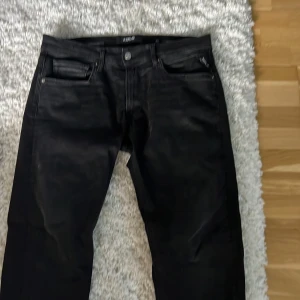 Svarta Replay Grover Hyperflex jeans - Svarta jeans från Replay, modell Grover Hyperflex. Klassisk femficksdesign med Replay-logga på fickan och bak, samt snygga detaljer i silver. Jeansen är tillverkade i stretchigt material för extra komfort och har en stilren look.