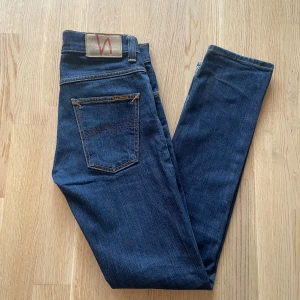 Mörkblå Nudie Jeans Grim Tim W29 L32 - Jag säljer dom här riktigt feta Nudie Grim Tim jeansen som är i storlek W29 L32. Dom är använda men fortfarande i bra skick. Tveka inte att höra av er! Mått Längd: 99cm Midja: 37cm