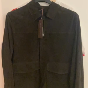 Oscar Jacobson mocka jacka - Snygg mörkbrun overshirt från Oscar Jacobson i mjuk mocka. Aldrig använt bara legat på hyllan. Prislappen fortfarande kvar. Säljer pga för liten