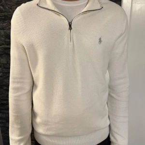 Vit half zip tröja från Polo Ralph Lauren - Säljer en stilren vit tröja från Polo Ralph Lauren med half zip och broderad logga på bröstet. Tröjan är långärmad och har en klassisk passform. Perfekt för dig som gillar en clean och tidlös look. Köpt på Åhléns, nypris 2500kr 