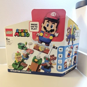 LEGO Super Mario Adventures with Mario Starter Course 71360 - LEGO Super Mario Starter Course 71360 med interaktiv Mario-figur. Komplett med alla delar och originalkartong. Fint skick, inga synliga defekter, förutom viss skada på kartongen där man öppnade förpackningen. Perfekt för barn och fans av Super Mario som vill bygga och spela interaktivt.