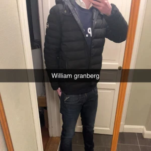 Svart pufferjacka med huva - Säljer en svart pufferjacka från Colmar med huva och dragkedja framtill. Jackan har en quiltad design och en normal passform, perfekt för kyligare dagar. Enkel och stilren look som passar till det mesta. Allt og medföljer