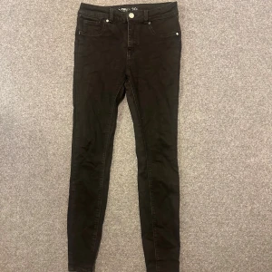 Svarta skinny jeans - Svarta skinny jeans med klassisk femficksdesign och smal passform hela vägen ner. Byxorna har normal midja och är tillverkade i ett stretchigt jeanstyg som sitter tajt och bekvämt. Perfekta för dig som gillar en stilren och enkel look.