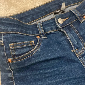 Blå bootcut jeans från HM, stl 34 - Snygga blå jeans från HM i klassisk bootcut-modell. Jeansen har låg midjad midja, fem fickor och kontrastsömmar. Materialet är klassiskt denim med lite stretch för skön passform. Perfekta för dig som gillar en tidlös look med lite utsvängda ben.