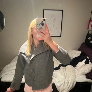 Grå kappa från Gina Tricot💗 - Grå kappa från Gina Tricot med bred krage och tre stora knappar framtill. Jag säljer den jackan för den är för liten och för kort💗Perfekt för dig som gillar stilren och enkel look. Det är stolek 134/140. Den är lite sönder i där man sätter up den på krokar🫶🏼