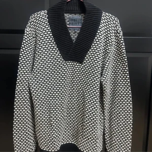 Svartvit stickad tröja från Blue Print -  stickad tröja från Blue Print i svartvitt mönster. Tröjan har en bred ribbad krage i svart och lång ärm. 