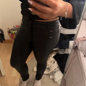 Svarta skinn byxor med dragkedjor - Säljer ett par svarta skinny byxor med snygga detaljer framtill 