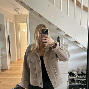 Beige overshirt med stora fickor - Snygg beige kappa med stora framfickor och bred krage. Säljer på grund av att den inte kommer till användning längre! Perfekt nu till hösten!💕💕
