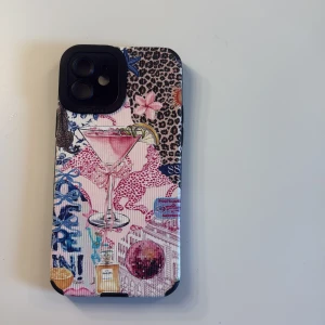 iPhone 12/12 Pro Skal - Cocktail & Leopard Mönster - Unikt skal för iPhone 12/12 Pro med färgglatt cocktail- och leopardmönster. Skalets yta är texturerad och ger bra grepp. Kameraskydd med 'Pro Camera' märkning. Skalet är i gott skick utan synliga skador eller slitage. Perfekt för dig som vill ha ett personligt och skyddande mobilskal.