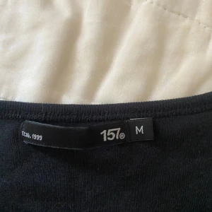 Svart långärmad tröja från 157 - En basic svart långärmad tröja från 157 med rund halsringning. Perfekt att styla med jeans eller kjol för en clean look. Tillverkad i mjuk bomull som känns skön mot huden.