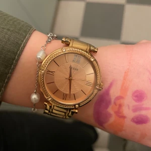 Guldig klocka från Guess med länkarmband - Säljer min kompis guess klocka. Den är i bra skick, nästan inte använd!! Den går för typ 1200kr men säljer endast för 899kr då den knappt är använd!
