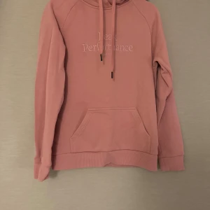 Rosa hoodie från Peak Performance - Säljer en snygg rosa hoodie från Peak Performance med broderad logga på bröstet. Tröjan har huva med snörning, magficka och långa ärmar. Perfekt för chill dagar och har en skön, mjuk känsla.