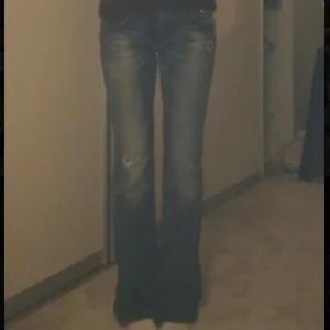 Miss Me jeans - Skitsnygga bootcut jeans från Miss Me med slitningar och ljusa tvättade partier. Jeansen har låg midja, dekorativa bakfickor med broderier och klassisk femficksdesign. Perfekta för dig som gillar en avslappnad och trendig look.