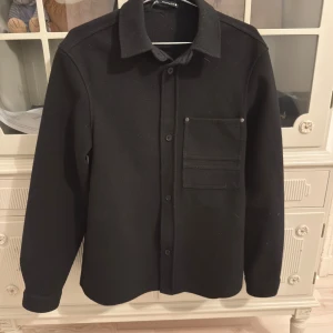 Svart overshirt från Zara - Svart overshirt från Zara i storlek S. Sparsamt använd, i bra skick, köpt på Zara för 500kr