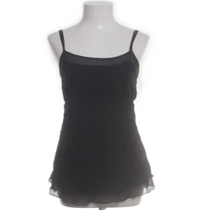 Svart linne 100% silke Karl Lagerfeld H&M - Svart linne i 100% silke från Karl Lagerfeld for H&M med tunna justerbara axelband och knappar där bak. Linnet har en lätt, luftig känsla och är perfekt för dig som gillar minimalistisk och stilren design. Passar dig som vill ha något klassiskt men ändå trendigt. Funkar bra både till vardags och fest. Har ett litet hål längst ner, men märks inte när man har på sig det, då tyget är i flera lager. Storlek 36, motsvarar storlek S. Gott skick.