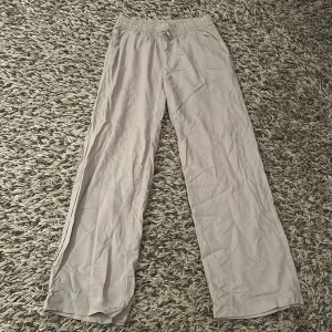 Beiga vida linnebyxor med snörning - Säljer ett par beiga linnebyxor med bred passform och resår i midjan samt snörning framtill. Byxorna har fickor fram och en ficka bak. Perfekta för en chill och avslappnad stil. Lätta och luftiga i materialet, passar grymt till sommaren.💗Aldrig använda och lappen sitter kvar