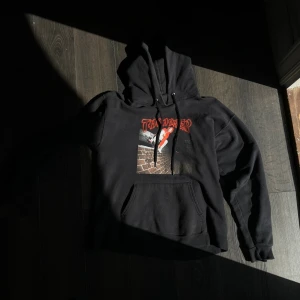 Svart Thrasher hoodie M  - Svart hoodie från Thrasher med fett tryck framtill i rött och en bild på en skateboardåkare. Klassisk känguruficka och snörning i huvan. Perfekt för dig som gillar streetstyle och skatevibes.